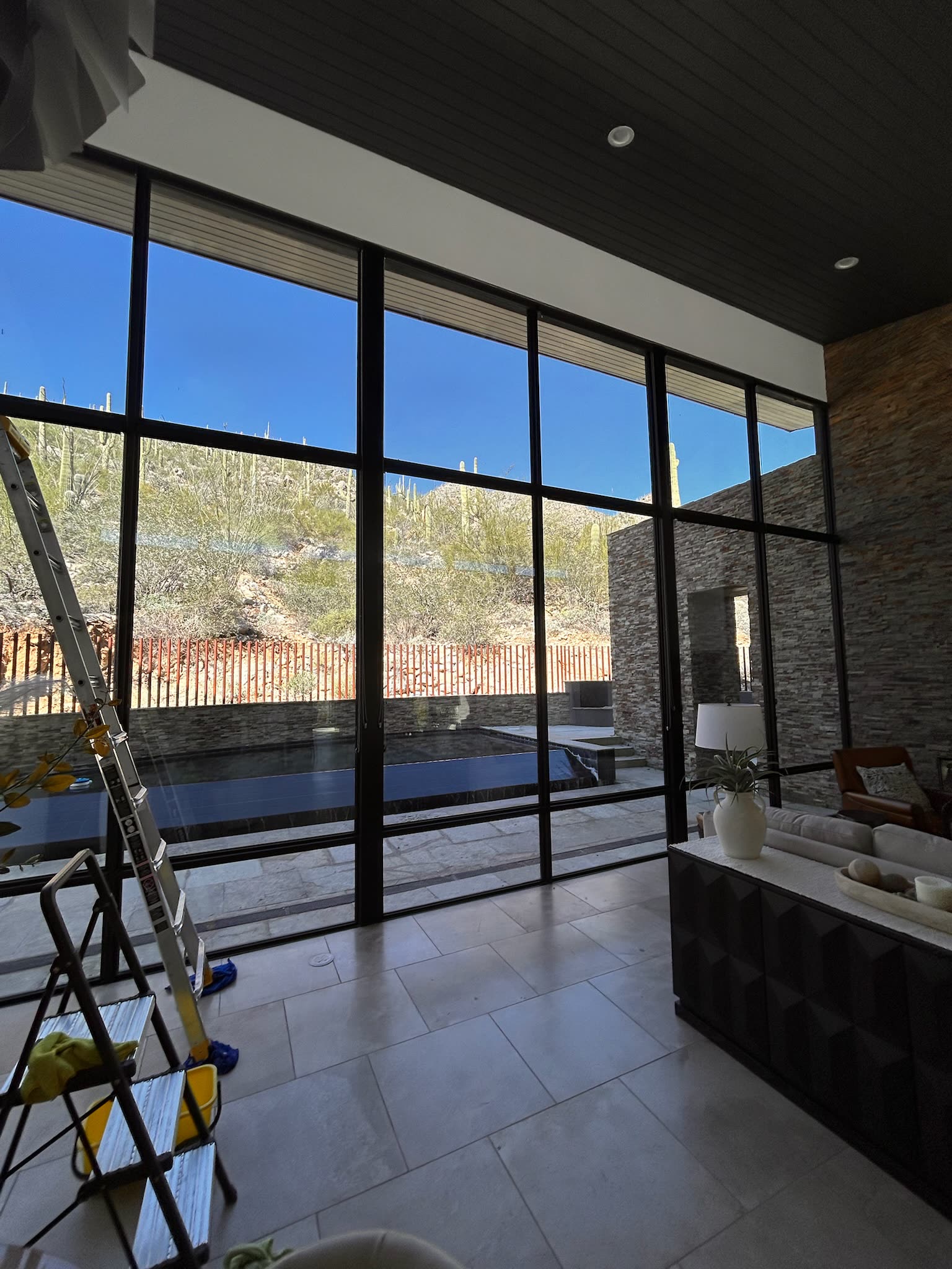 Spotless glass wall overlooking a pool and desert hillside