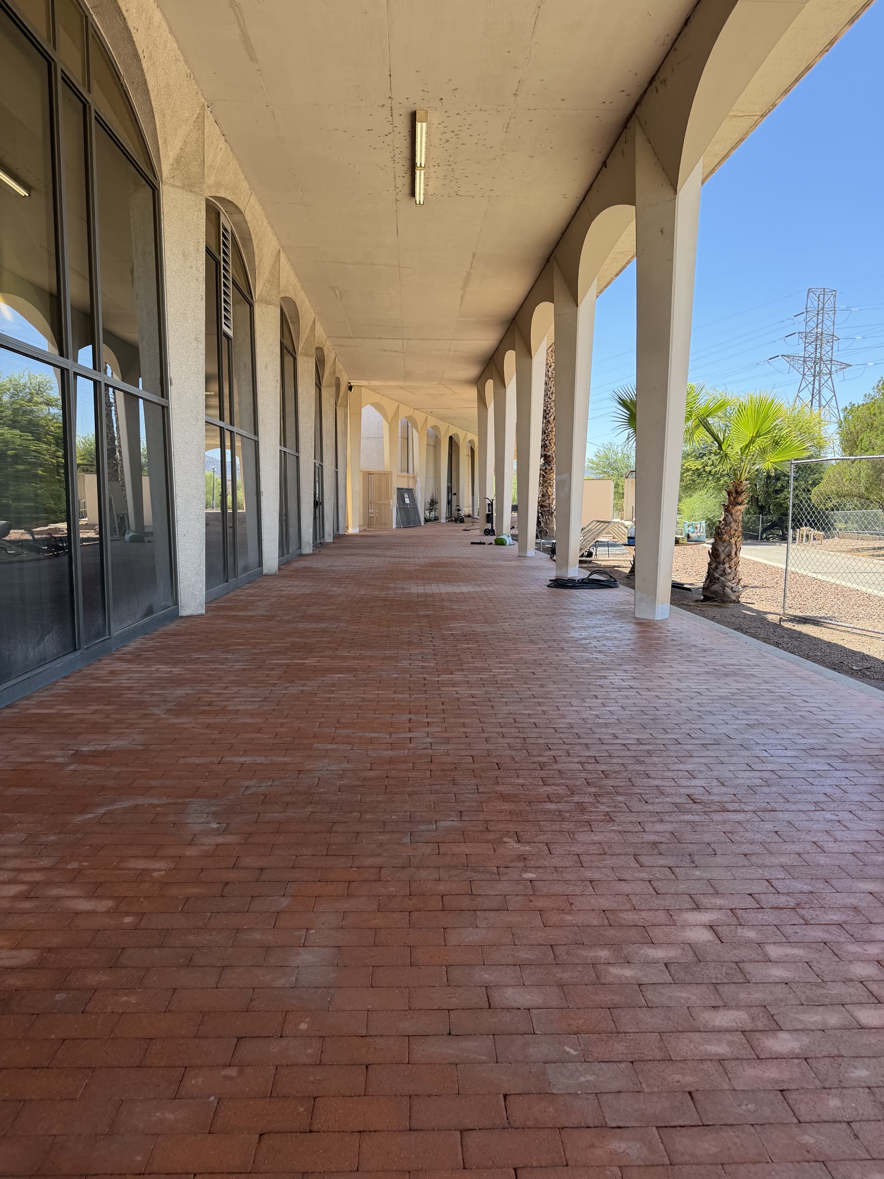 Freshly pressure-washed brick paver walkway along an arched colonnade