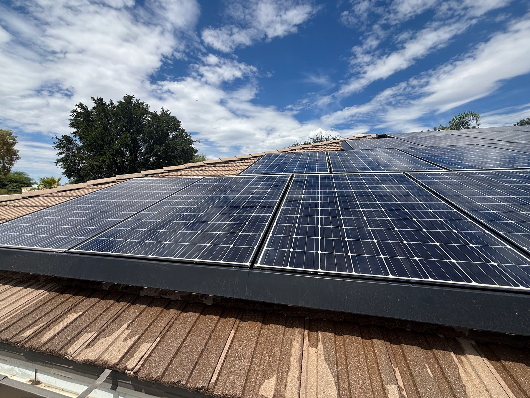 Freshly cleaned rooftop solar panel array under a blue sky